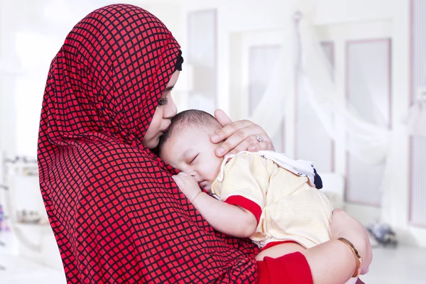 Mother with veil kiss her baby in bedroom — Stockfoto