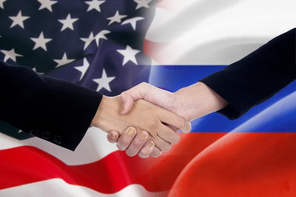 People handshake with the russian and american flags — Stockfoto