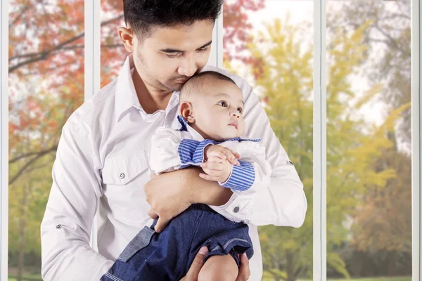 Papá sostiene y besa a su bebé en casa —  Fotos de Stock