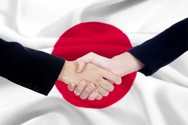Aperto de mão com uma bandeira japonesa fundo — Fotografia de Stock