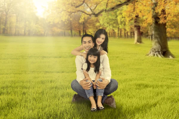 Familia feliz sentado en la hierba en la temporada de otoño — Foto de Stock