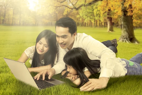 Happy family with laptop at autumn park — Stock Photo, Image