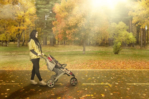 Mother with carriage going for a walk in — Stock Photo, Image