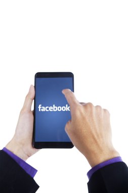 Finger touching smartphone screen with facebook logo