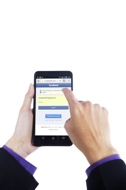 Hand touching smartphone screen with facebook site