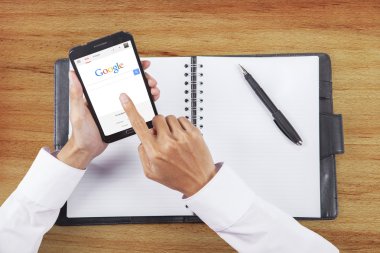 Hand using google search engine on smartphone