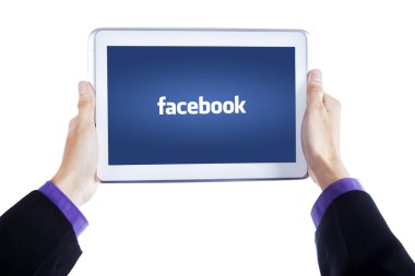 Hands holding tablet with facebook logo on screen