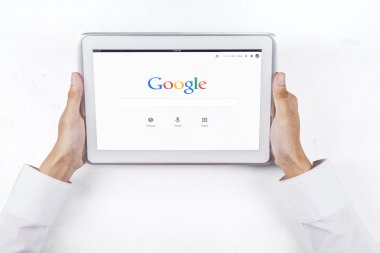 Hands holding tablet with google webpage
