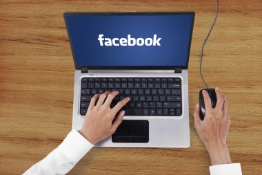 Hands using laptop with facebook logo