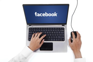 Hands with facebook logo on the laptop screen