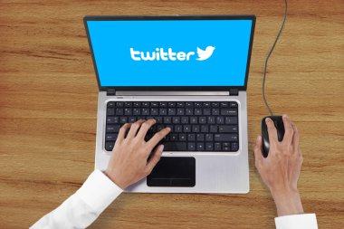 Worker hands typing on laptop with twitter logo