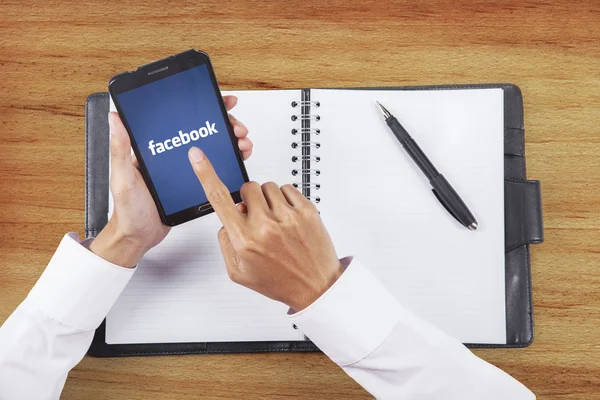 Hand touching facebook logo on the smartphone screen — Stok fotoğraf