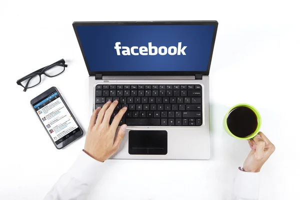Manos con el logotipo de facebook en el portátil — Foto de Stock