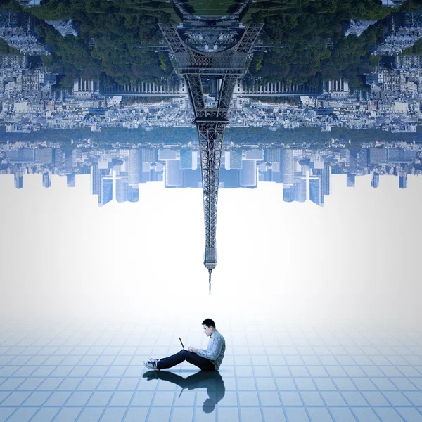 Man using laptop under upside down city — Stock Photo, Image