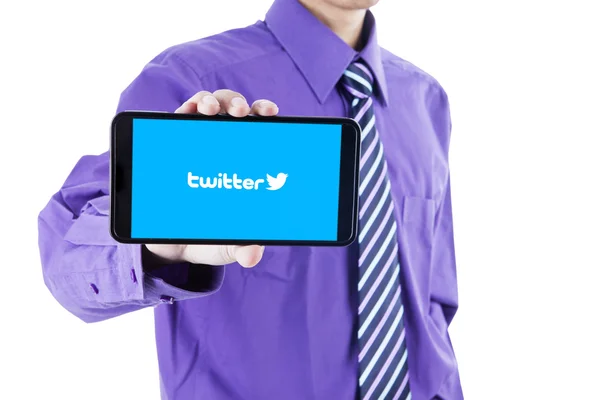 Человек, показывающий символ твиттера с сотовым телефоном — стоковое фото