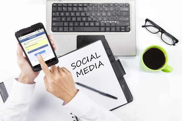 Worker accesses facebook site with cellphone — Stock Photo, Image