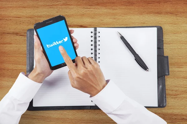 Arbeiter hält Handy mit Twitter-Logo in der Hand — Stockfoto
