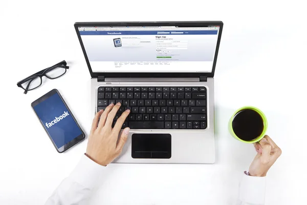 Werknemer houdt koffie terwijl facebook site te openen — Stockfoto