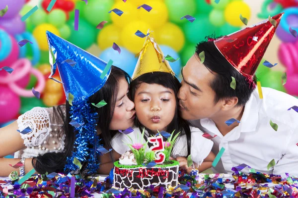 Chica soplando vela de cumpleaños con los padres —  Fotos de Stock