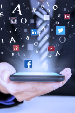 Businessman holds smartphone with social media symbols