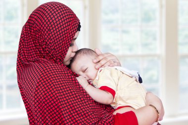 Muslem woman and her baby at home clipart