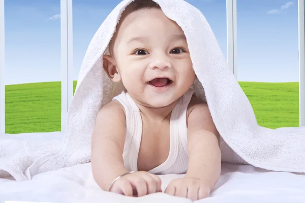 Веселый ребенок играет с полотенцем на кровати — стоковое фото