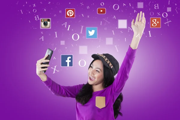 Cheerful teenage girl holds cellphone with social media logo — Stockfoto