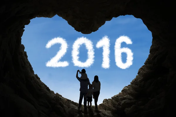 Szczęśliwa rodzina wewnątrz jaskini patrząc na numery 2016 — Zdjęcie stockowe