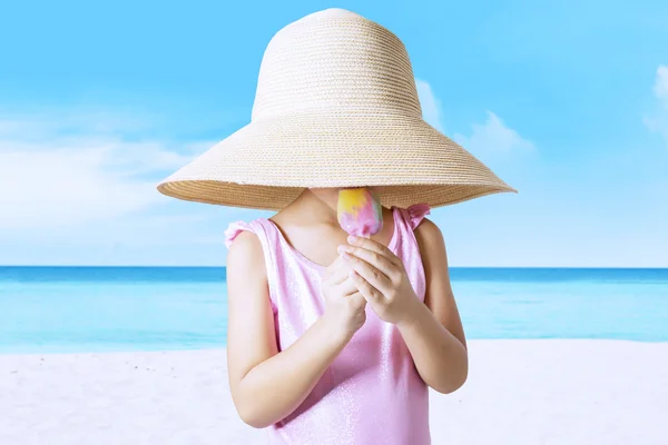 Little kid with hat licks ice cream at coast — Stock Photo, Image