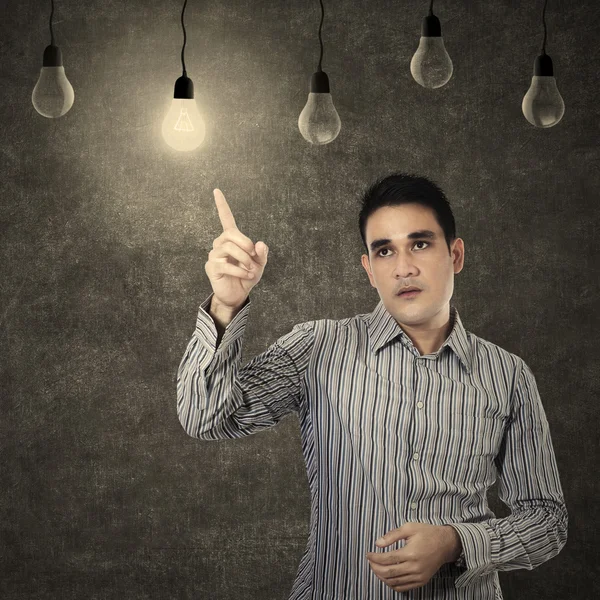 Man pointing at lit lightbulb — Stock Photo, Image