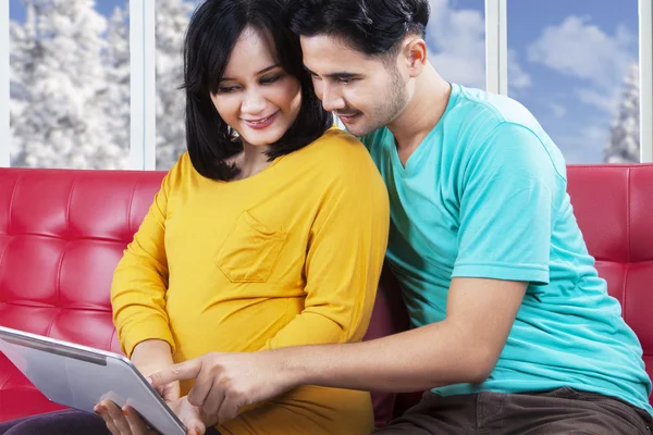 Adam hamile karısıyla tablet kanepe üzerinde kullanma — Stok fotoğraf