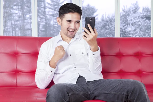 Homme à succès avec téléphone portable sur canapé — Photo