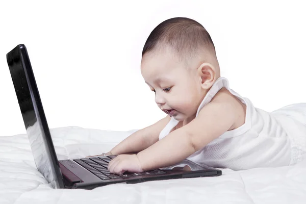 Criança curiosa jogando notebook na cama — Fotografia de Stock