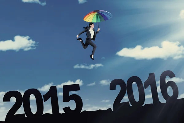 Female worker with umbrella jumping on the sky — Stock Photo, Image