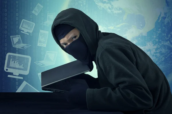 Man met masker stealing zakboekje computer — Stockfoto