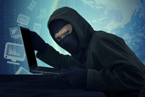 Robber with mask stealing notebook computer — Stock Photo, Image