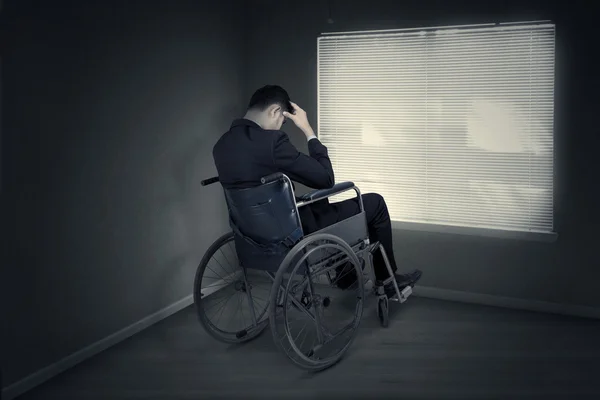 Stressful man sitting on the wheelchair near the window — Stock Photo, Image