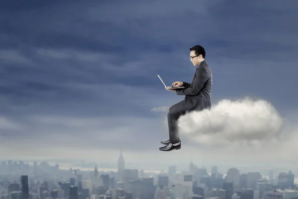 Businessman using laptop on the cloud — Stock Photo, Image