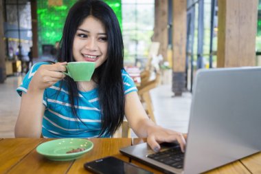 dizüstü bilgisayar kullanırken kahve içme kadın