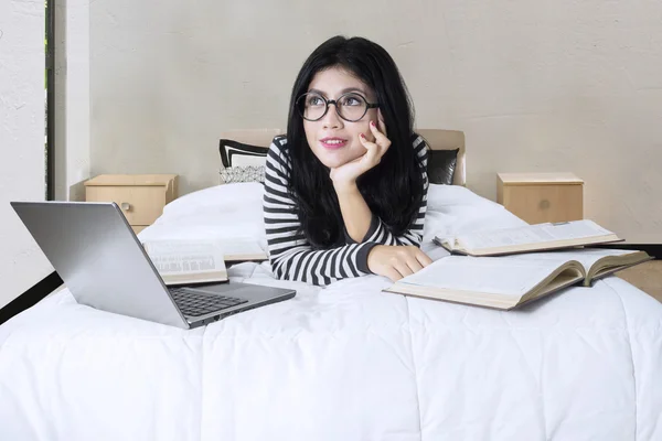 Asiatin liegt mit Laptop und Büchern im Bett — Stockfoto