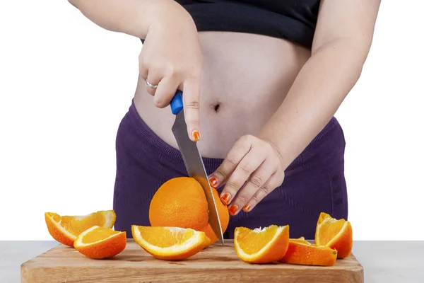 Zwangere vrouw snijden vers oranje fruit — Stockfoto