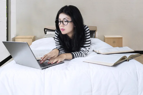 Studentin macht Hausaufgaben auf dem Bett — Stockfoto