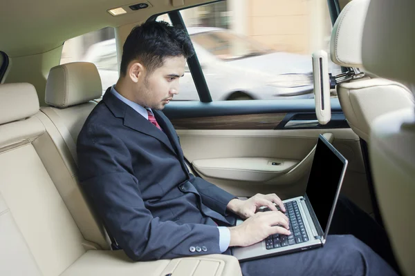 Hombre trabajando con el ordenador portátil en el coche — Foto de Stock