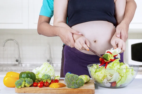 Pregnant wife making salad with her husband — Stock Photo, Image