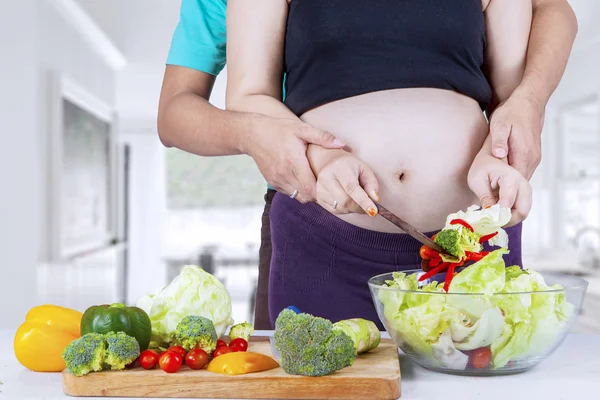 Zwangere vrouw en man koken in de keuken — Stockfoto