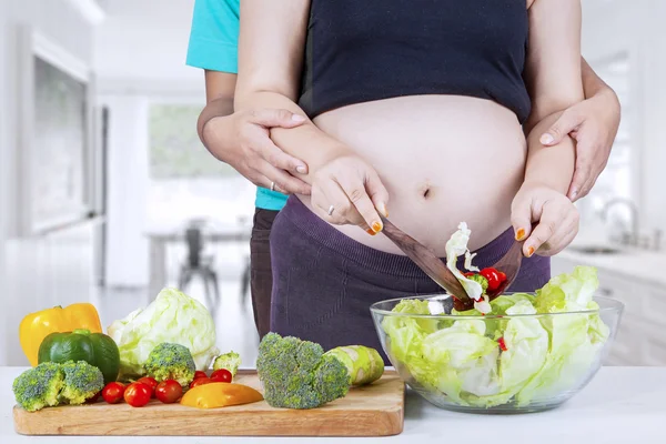 Hamile kadın kocasıyla salatası yapmak — Stok fotoğraf