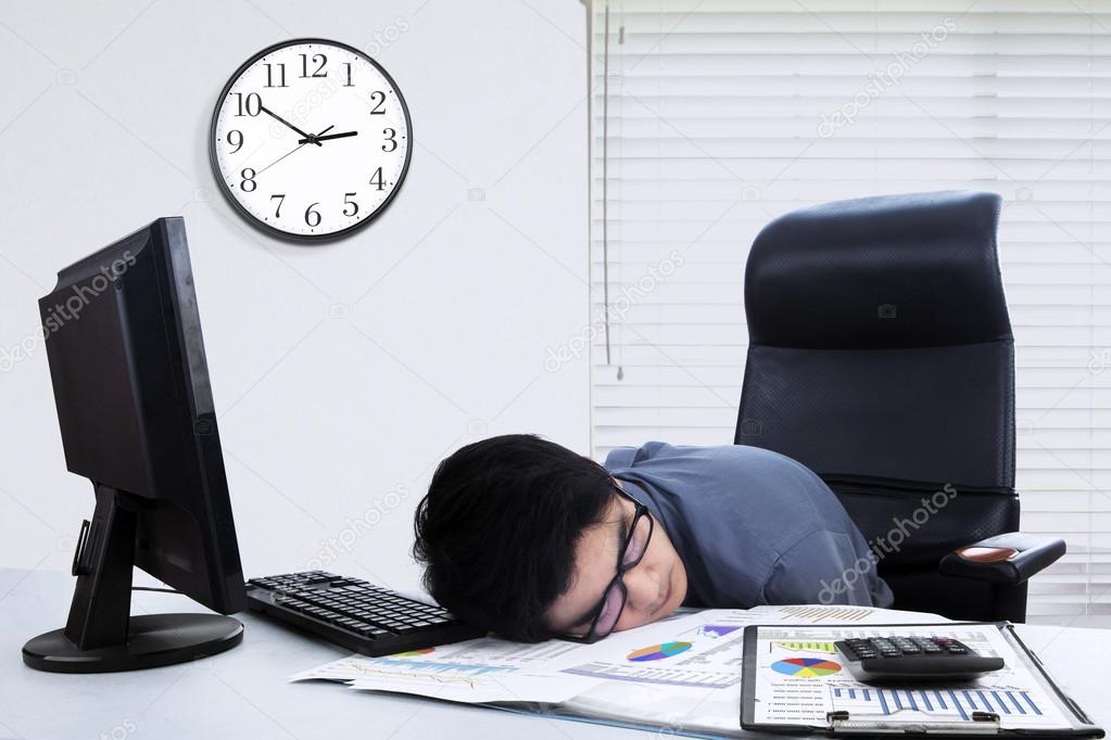 Male worker sleeping on the table in office