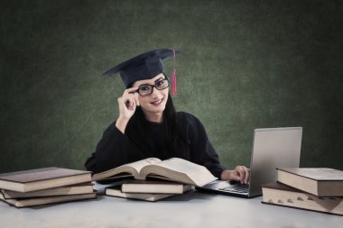 Kadın mezunu kitap ve dizüstü bilgisayar ile eğitim