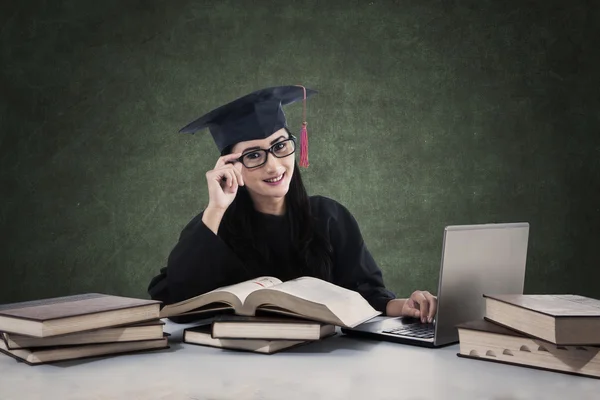 Mujer graduada estudiando con libros y laptop — Foto de Stock