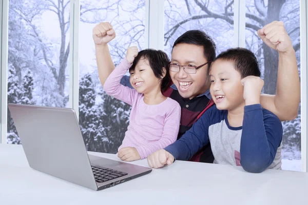 Två barn och pappa höja händer medan du använder laptop — Stockfoto